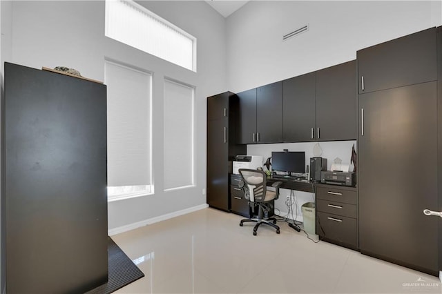 home office with a high ceiling, visible vents, and light tile patterned flooring