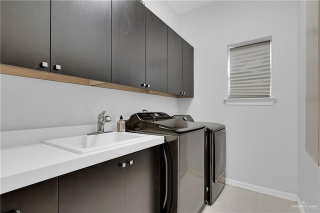 laundry room featuring cabinet space, light tile patterned floors, baseboards, independent washer and dryer, and a sink