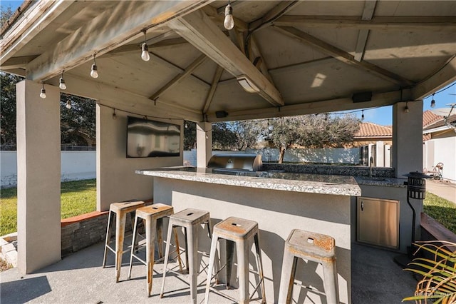 view of patio / terrace with a grill, a gazebo, fence, exterior kitchen, and outdoor wet bar