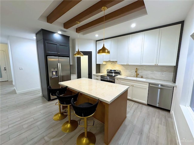 kitchen with tasteful backsplash, stainless steel appliances, sink, decorative light fixtures, and white cabinets