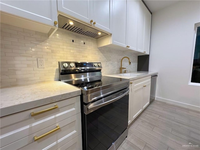 kitchen featuring appliances with stainless steel finishes, backsplash, light stone counters, sink, and white cabinetry