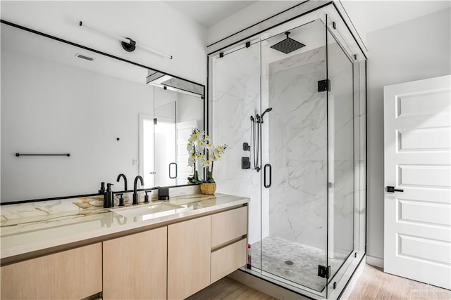 bathroom featuring vanity, an enclosed shower, and wood-type flooring