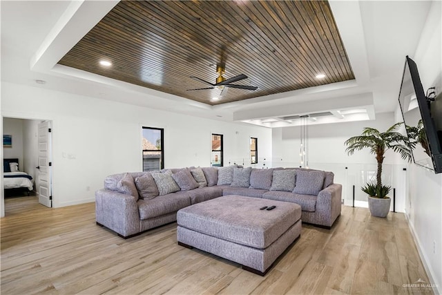 living room with a raised ceiling, ceiling fan, wooden ceiling, and light wood-type flooring