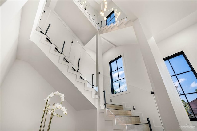 staircase with a high ceiling and a notable chandelier