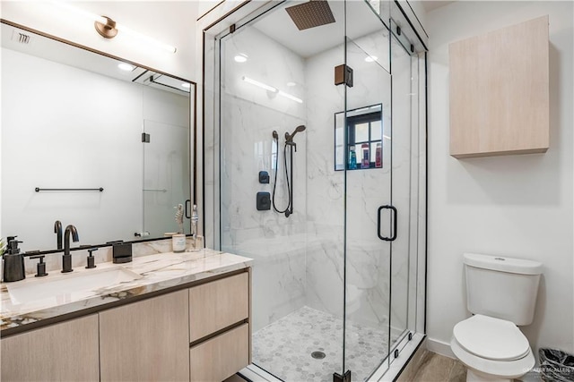 bathroom featuring vanity, an enclosed shower, and toilet