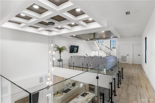 corridor featuring beamed ceiling, light wood-type flooring, and coffered ceiling