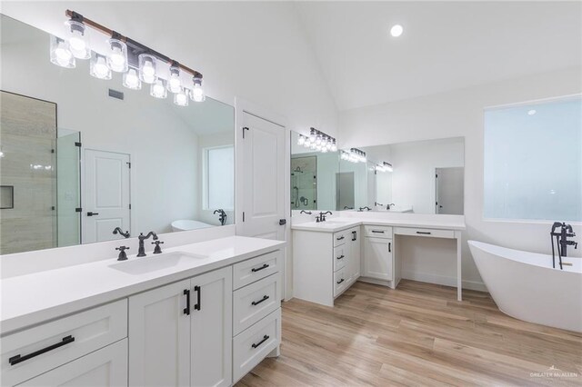 5706 N 44th Ln, Mcallen, TX 78504 - full bath with a shower stall, vaulted ceiling, two vanities, a freestanding bath, and wood finished floors