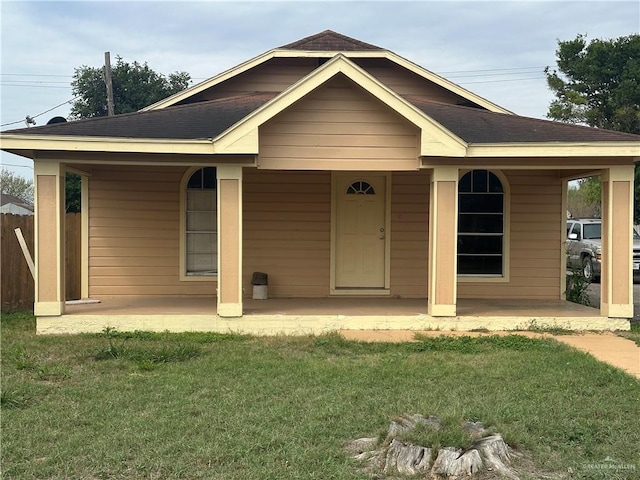 view of front of house featuring a shingled roof, fence, a front lawn, and a patio