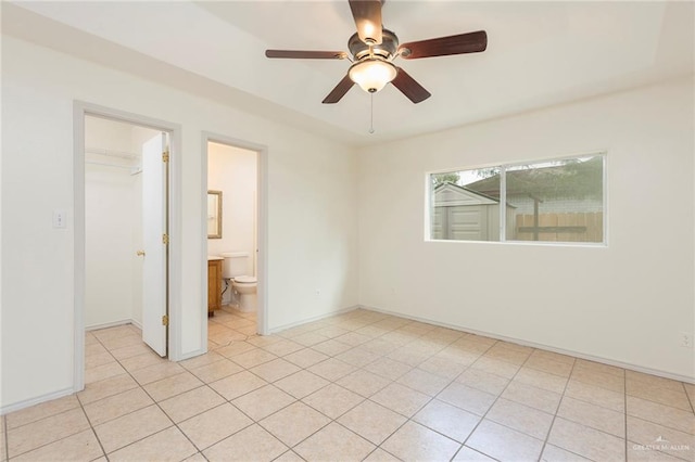 unfurnished bedroom featuring ceiling fan, a spacious closet, connected bathroom, a closet, and light tile patterned flooring