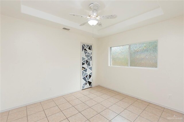 spare room featuring light tile patterned floors, a raised ceiling, and ceiling fan