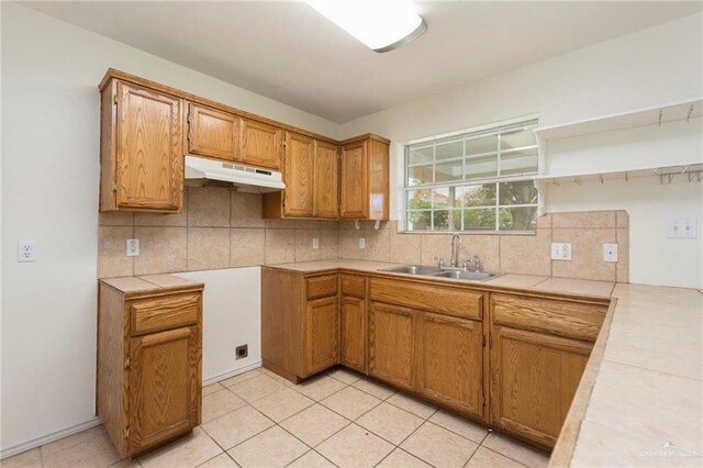 kitchen featuring tile counters, decorative backsplash, light tile patterned floors, and sink