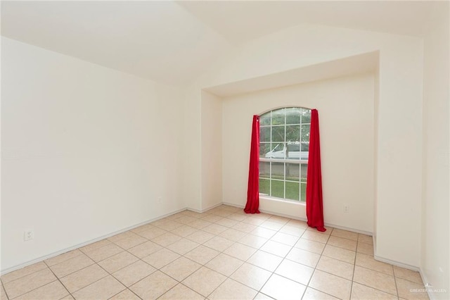 unfurnished room with light tile patterned floors and lofted ceiling