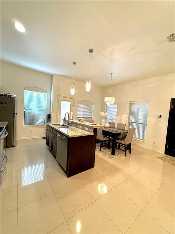 kitchen featuring light tile patterned flooring, sink, appliances with stainless steel finishes, an island with sink, and pendant lighting