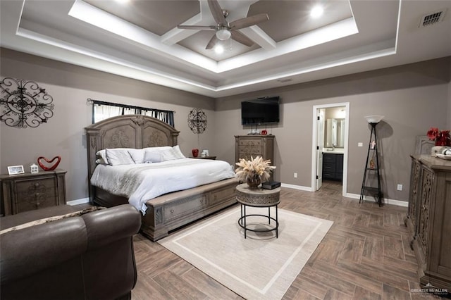 bedroom with a tray ceiling, dark parquet flooring, and ensuite bathroom