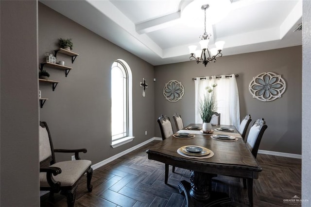 dining room with a notable chandelier, dark parquet flooring, and a raised ceiling