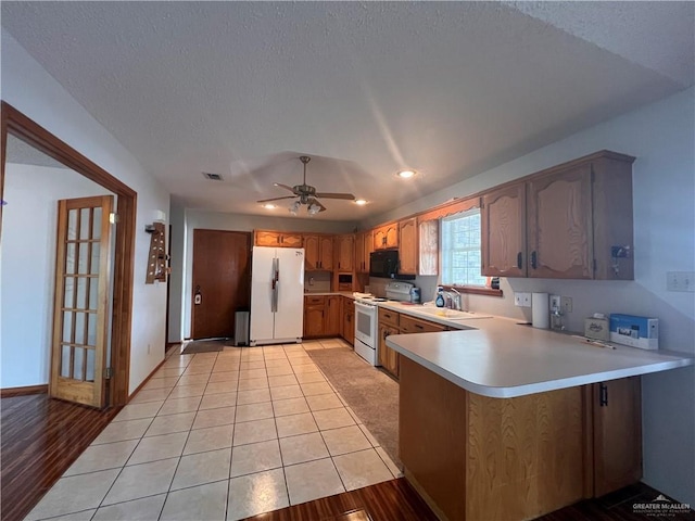 151 Tulip St, Mission, TX 78504 - kitchen featuring white appliances, a peninsula, light countertops, ceiling fan, and a textured ceiling