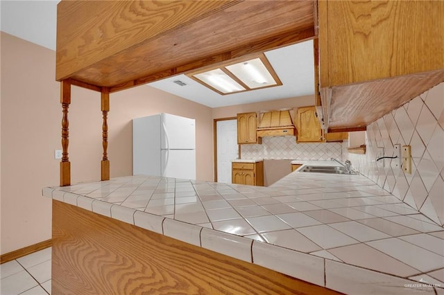 4113 Sonora Ave, Mcallen, TX 78503 - kitchen featuring a sink, freestanding refrigerator, light tile patterned floors, custom range hood, and visible vents