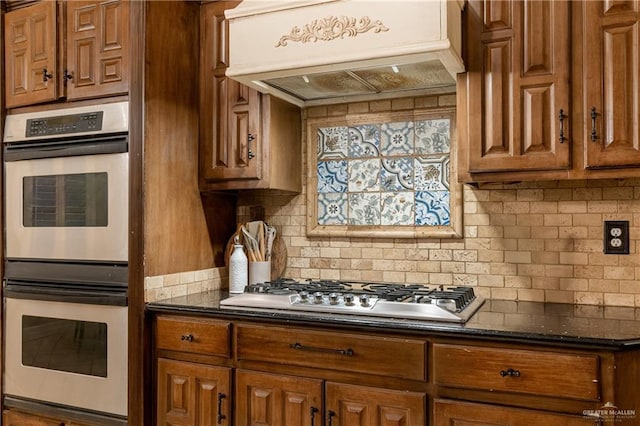 kitchen with tasteful backsplash, custom exhaust hood, dark stone counters, and appliances with stainless steel finishes