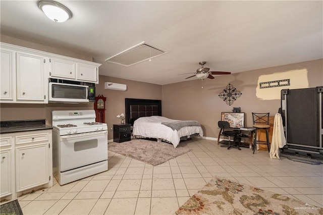 kitchen with light tile patterned floors, ceiling fan, white cabinetry, a wall unit AC, and white gas stove