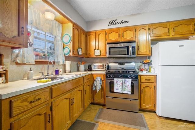 kitchen featuring stainless steel appliances, brown cabinets, light countertops, and a sink