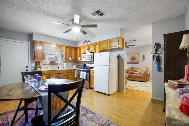 kitchen with brown cabinets, light wood finished floors, light countertops, visible vents, and appliances with stainless steel finishes