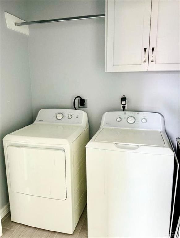 laundry area featuring light wood-type flooring, washer and dryer, and cabinet space