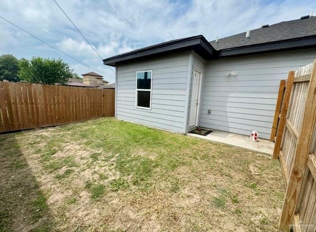 rear view of property with a fenced backyard, a lawn, and roof with shingles