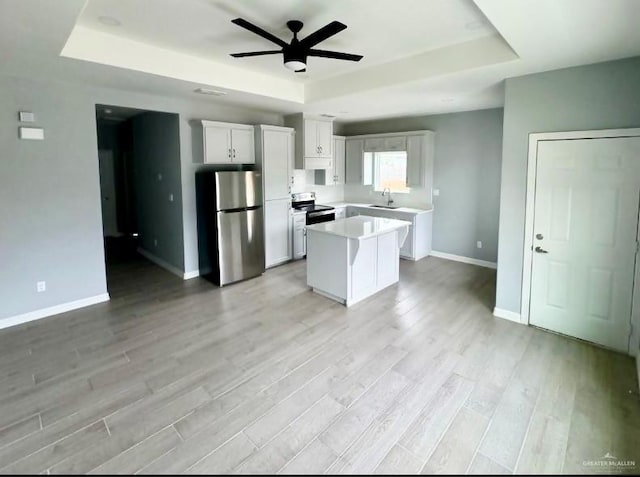 kitchen featuring stainless steel appliances, a tray ceiling, and light countertops