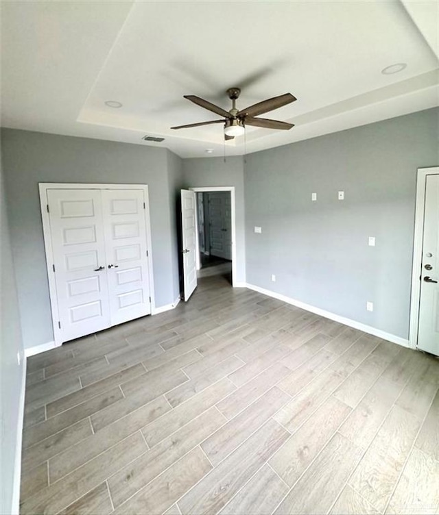 unfurnished bedroom with wood finish floors, visible vents, ceiling fan, and baseboards