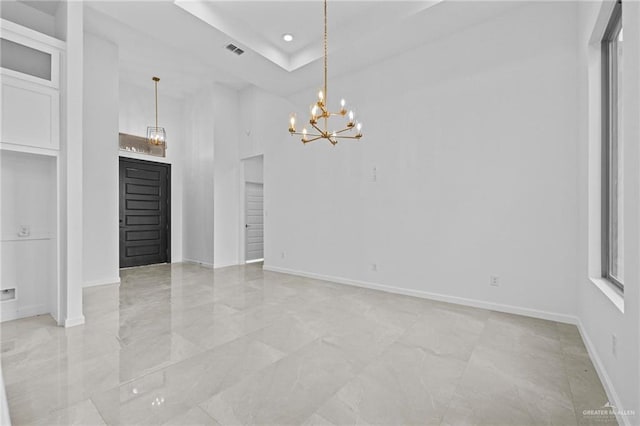 empty room featuring a chandelier and a tray ceiling