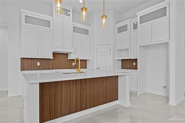 kitchen featuring a center island with sink, white cabinets, hanging light fixtures, and sink