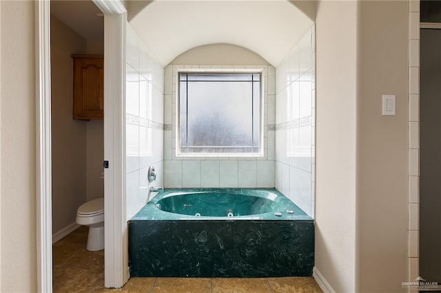 bathroom with tile patterned flooring, a whirlpool tub, and toilet