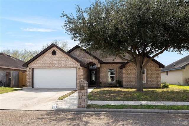 french provincial home featuring a garage, concrete driveway, and a front lawn