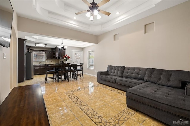 living area featuring visible vents, baseboards, a raised ceiling, ceiling fan with notable chandelier, and recessed lighting