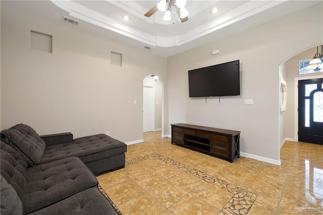 living area with visible vents, arched walkways, baseboards, a tray ceiling, and recessed lighting