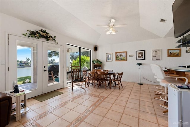 dining area featuring french doors, vaulted ceiling, ceiling fan, light tile patterned floors, and a water view