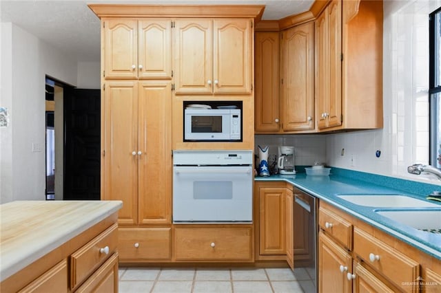 kitchen featuring tasteful backsplash, sink, light tile patterned floors, and white appliances