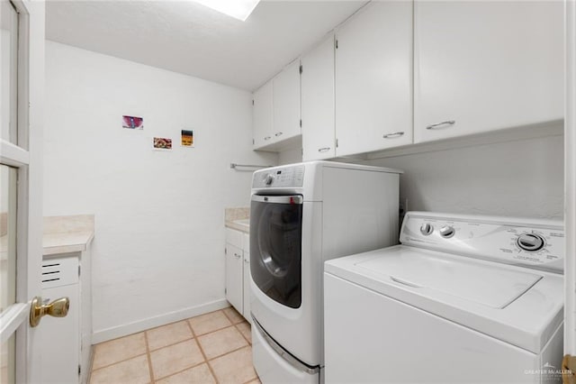 laundry room with washer and clothes dryer, cabinets, and light tile patterned floors