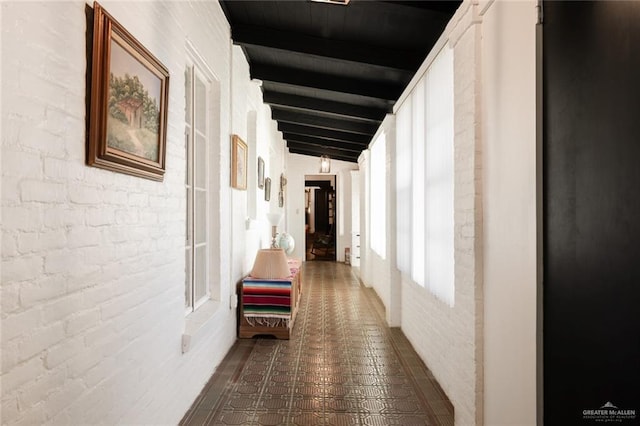 corridor featuring vaulted ceiling with beams and brick wall