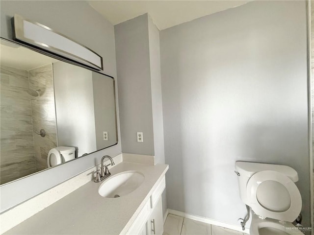 bathroom featuring toilet, baseboards, tiled shower, and vanity