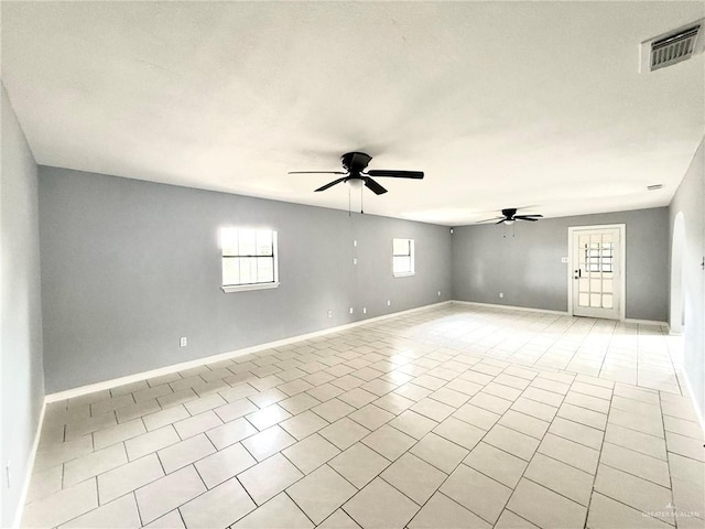 empty room with light tile patterned floors, ceiling fan, visible vents, and baseboards