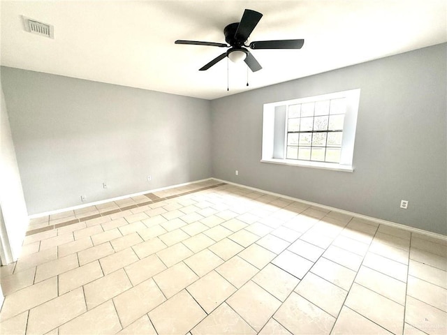 spare room featuring light tile patterned floors, baseboards, visible vents, and a ceiling fan