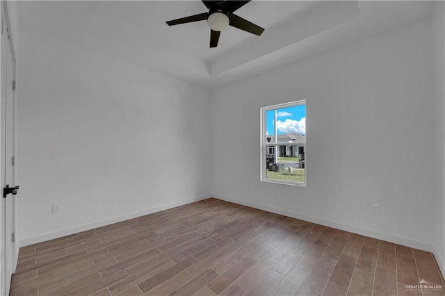 unfurnished room with a tray ceiling, ceiling fan, and light hardwood / wood-style floors