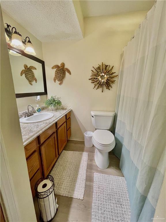 bathroom with toilet, vanity, a textured ceiling, and hardwood / wood-style floors