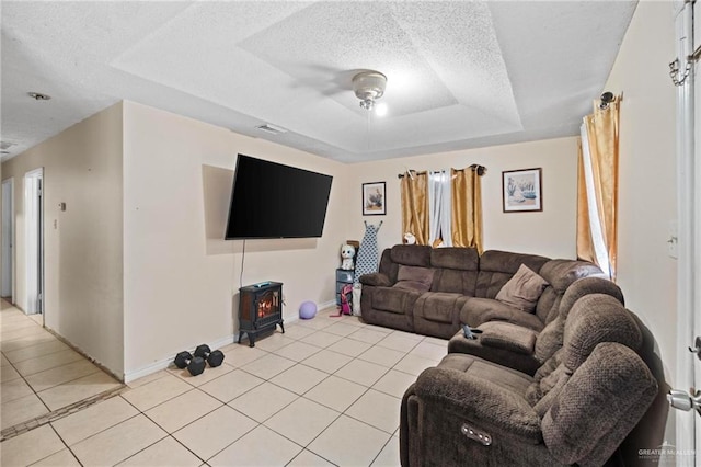 living room featuring a raised ceiling, a textured ceiling, and light tile patterned floors