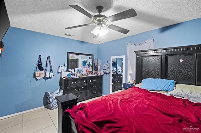 bedroom featuring a textured ceiling, ceiling fan, and light tile patterned flooring