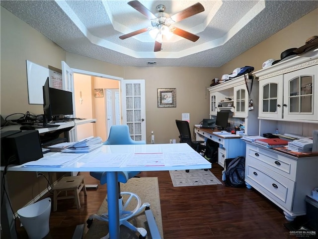 office featuring a textured ceiling, dark hardwood / wood-style flooring, a raised ceiling, and ceiling fan