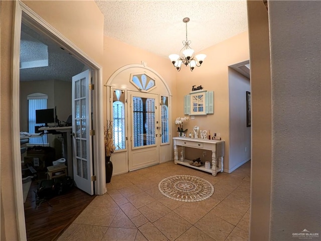 tiled foyer entrance featuring a chandelier and a textured ceiling