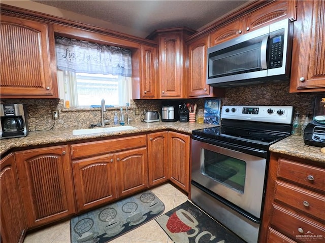 kitchen featuring light stone counters, light tile patterned floors, sink, and appliances with stainless steel finishes