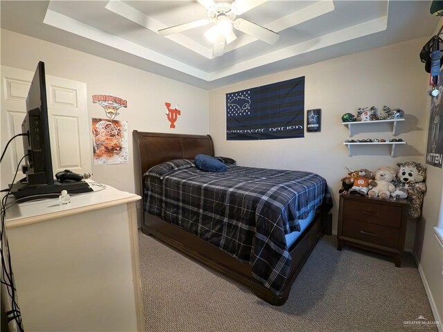 carpeted bedroom with a raised ceiling and ceiling fan